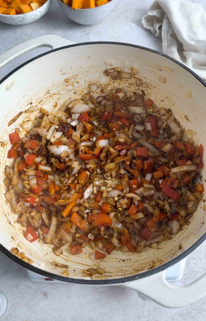 Diced onion, bell pepper and garlic mixed with spices in a pot.