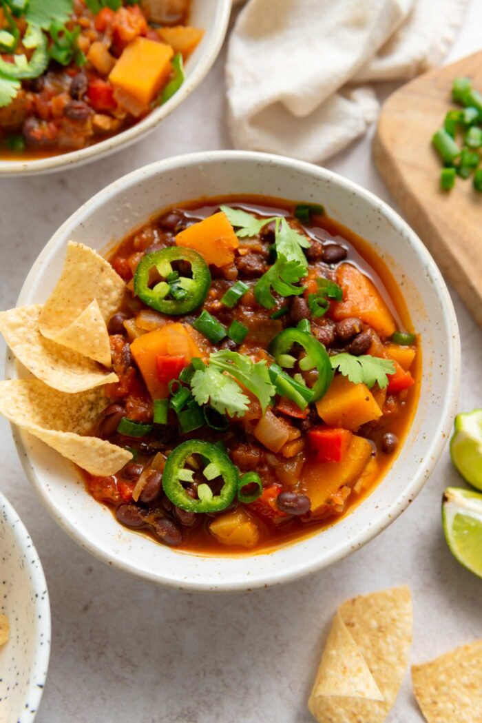 Bowl of butternut squash chili topped with jalapeno, green onion, cilantro and tortilla chips.