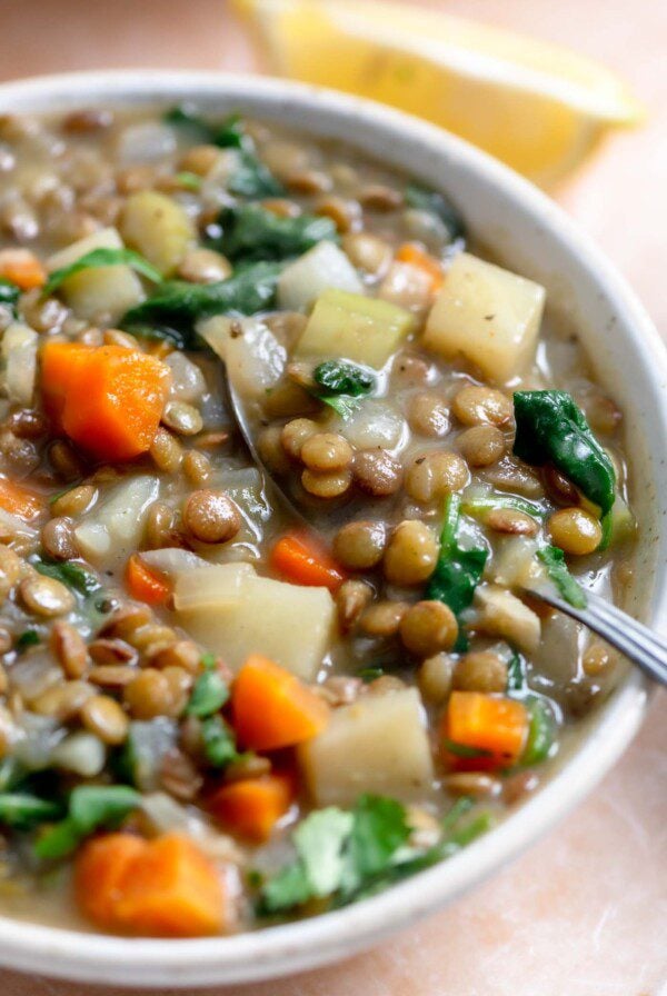 Bowl of lentil stew with potato, carrot and spinach.