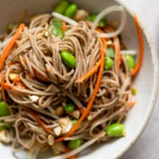 Bowl of miso soba noodles with carrot, bean sprouts and edamame.