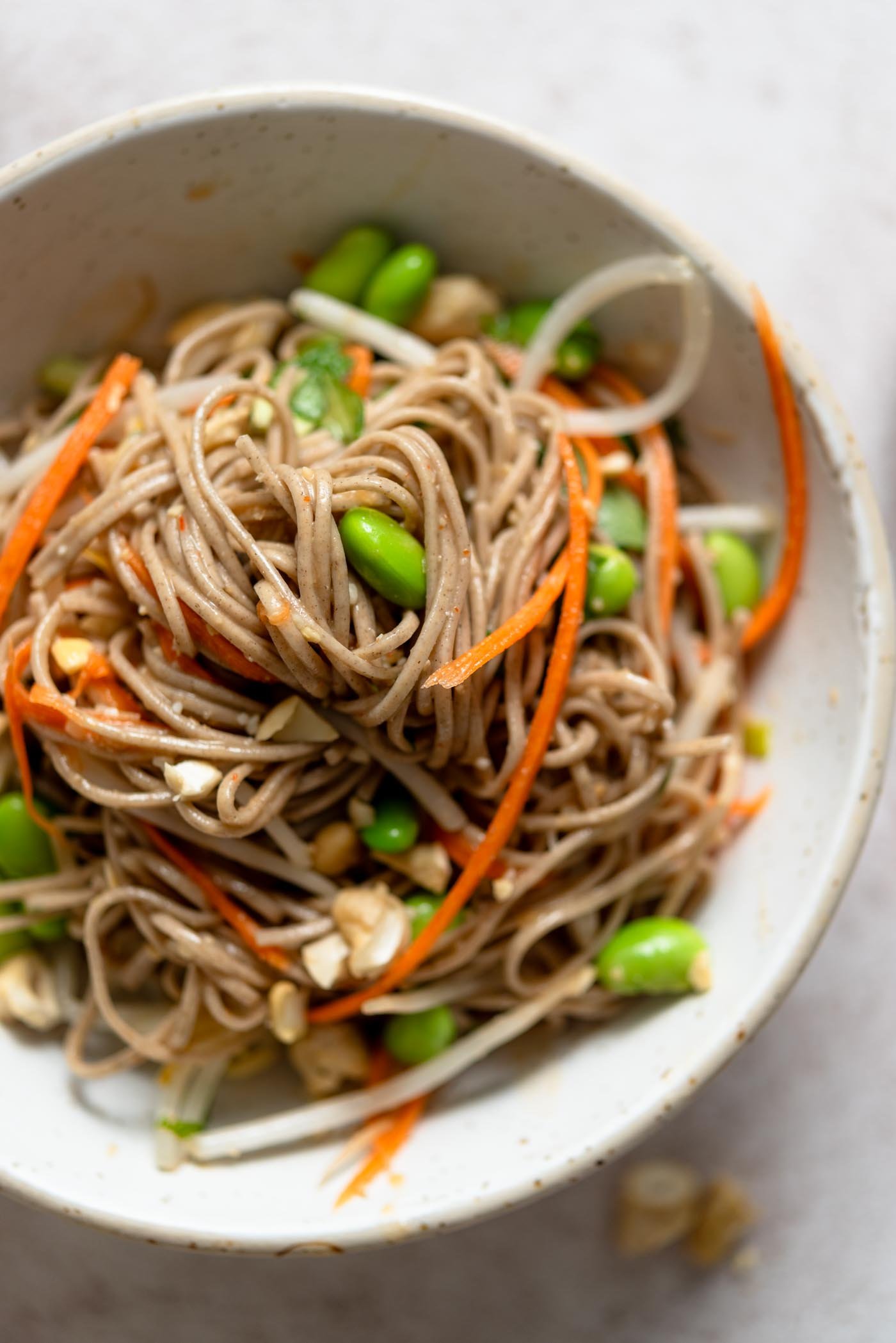 Bowl of miso soba noodles with carrot, bean sprouts and edamame.