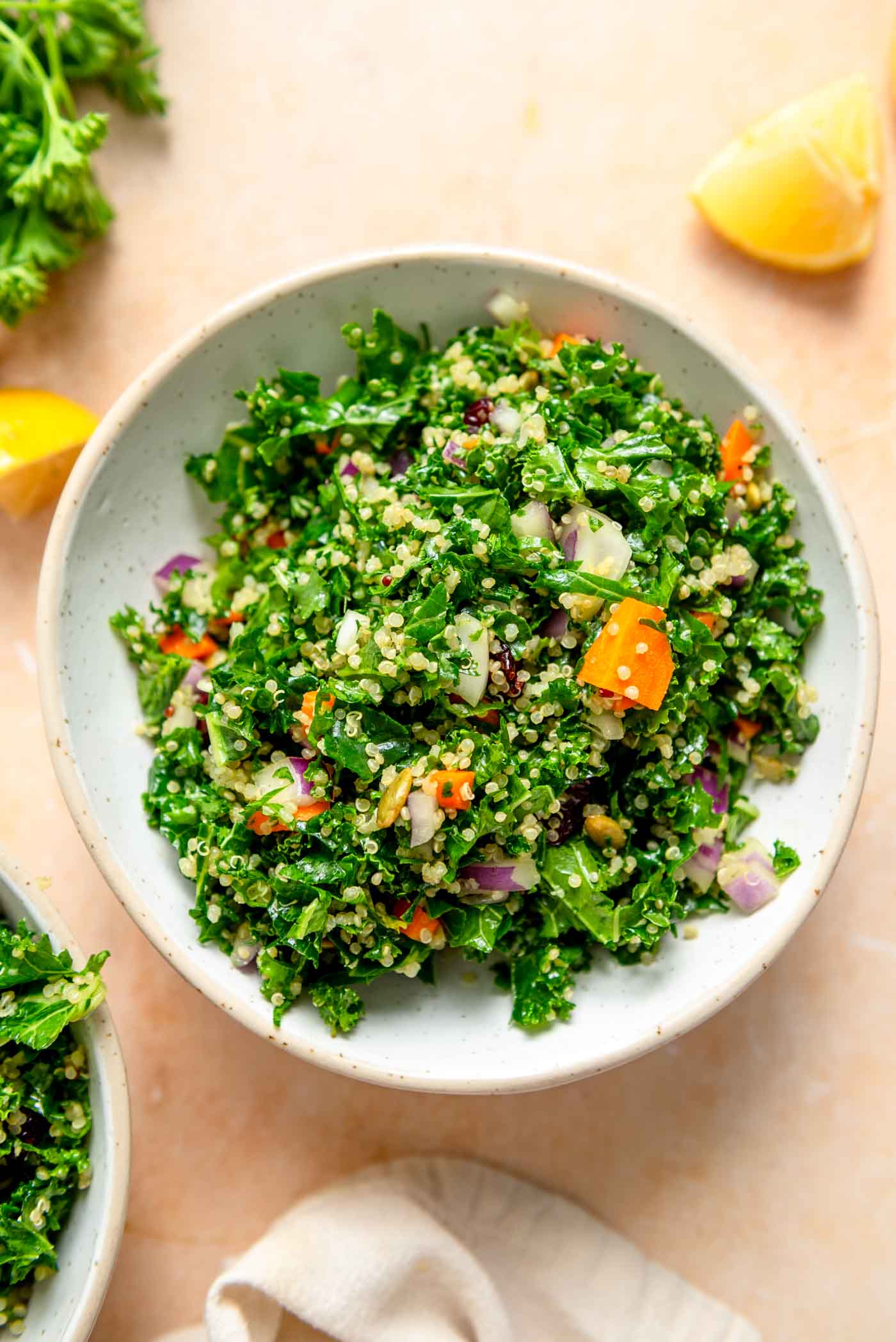 Bowl of kale quinoa salad with a wedge of lemon beside it.