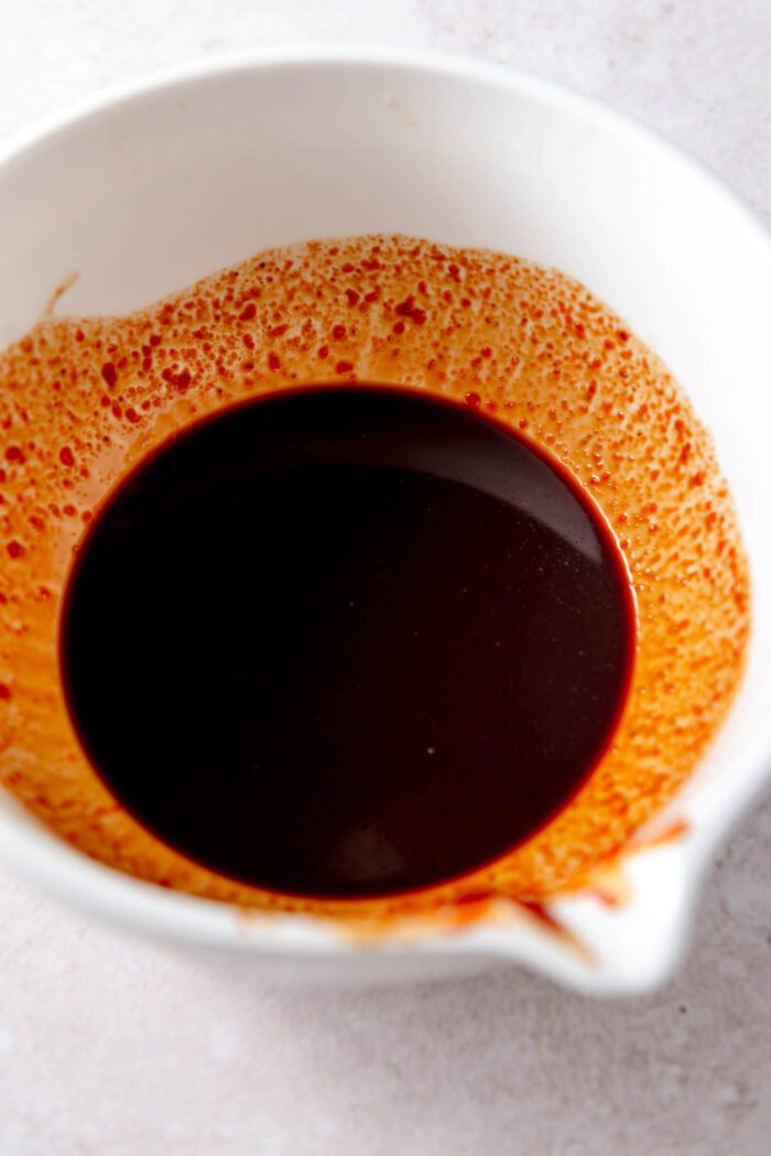 A dark sauce in a ceramic mixing bowl.