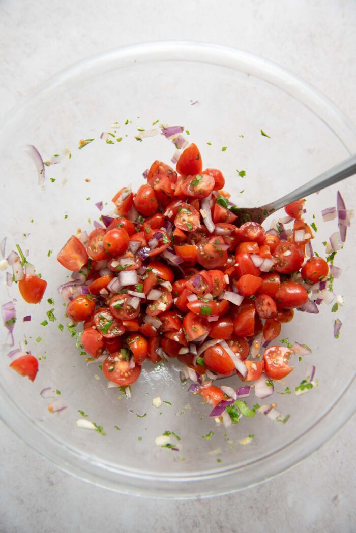 Bowl of chopped tomatoes mixed with red onion, parsley and garlic.