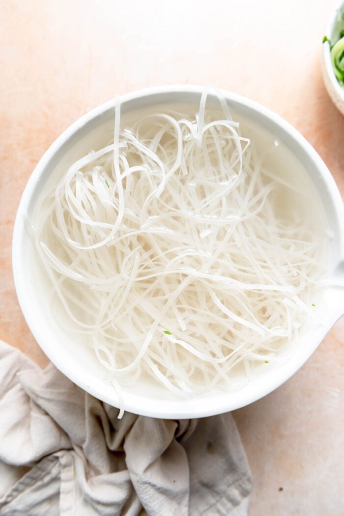 Rice noodles soaking in a bowl.