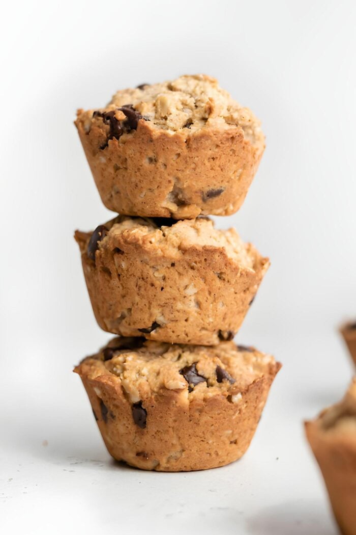 Stack of 3 vegan apple oatmeal protein muffins with chocolate chips.