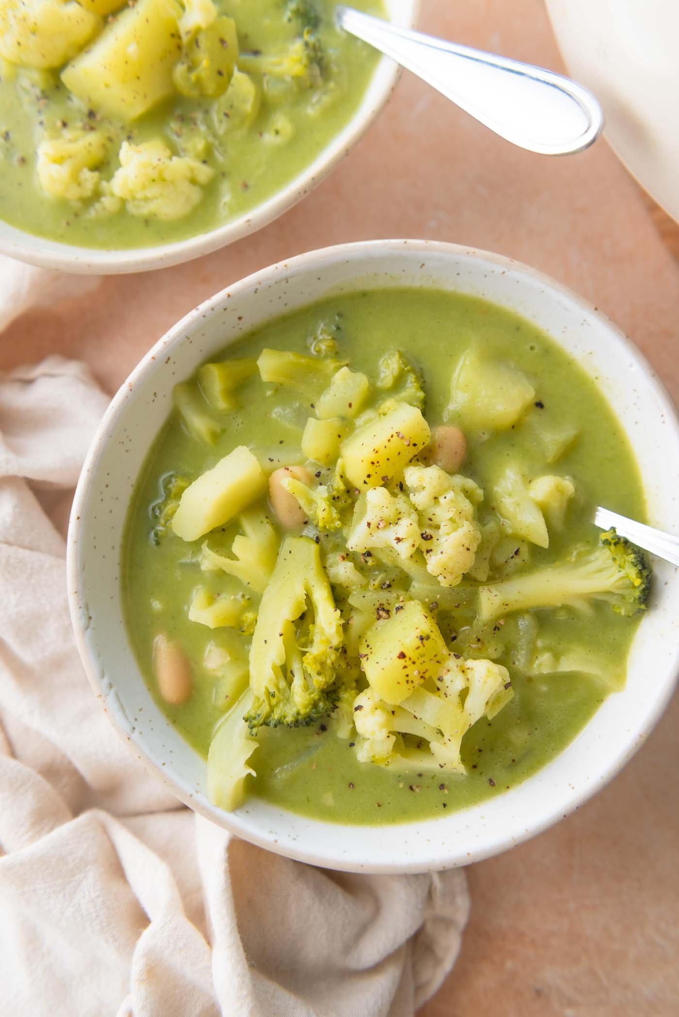 Bowl of soup with broccoli, cauliflower, white beans and potato.