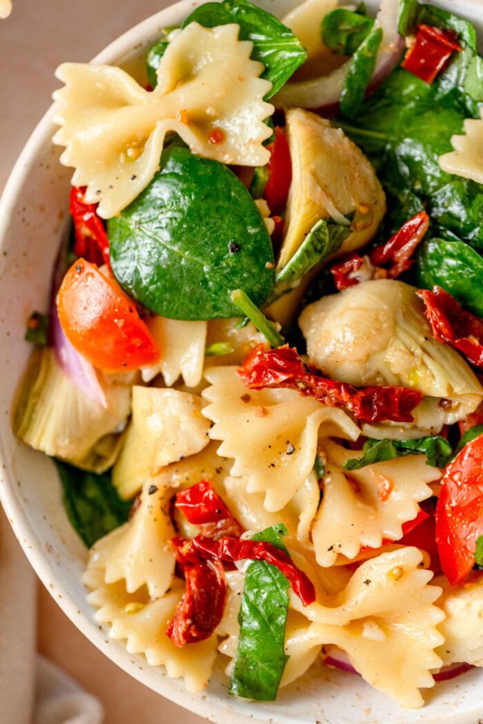 Bow tie pasta salad with sun dried tomatoes, spinach, cherry tomatoes and red onion.