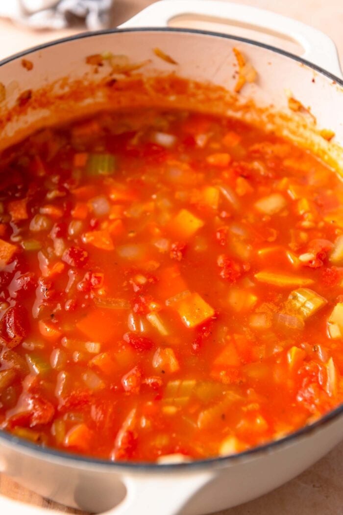 Tomato vegetable barley soup cooking in a large pot.