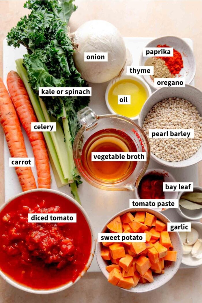 All the ingredients for a vegan vegetable barley soup recipe each labelled with text.