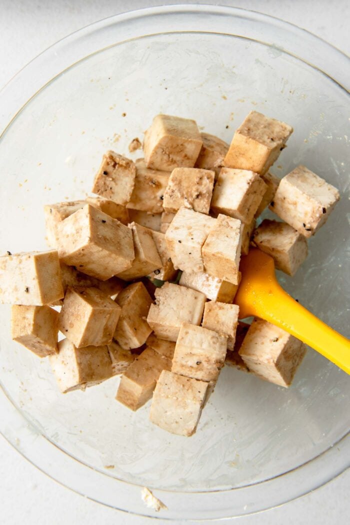 Cubes of tofu tossed in soy sauce in a bowl.