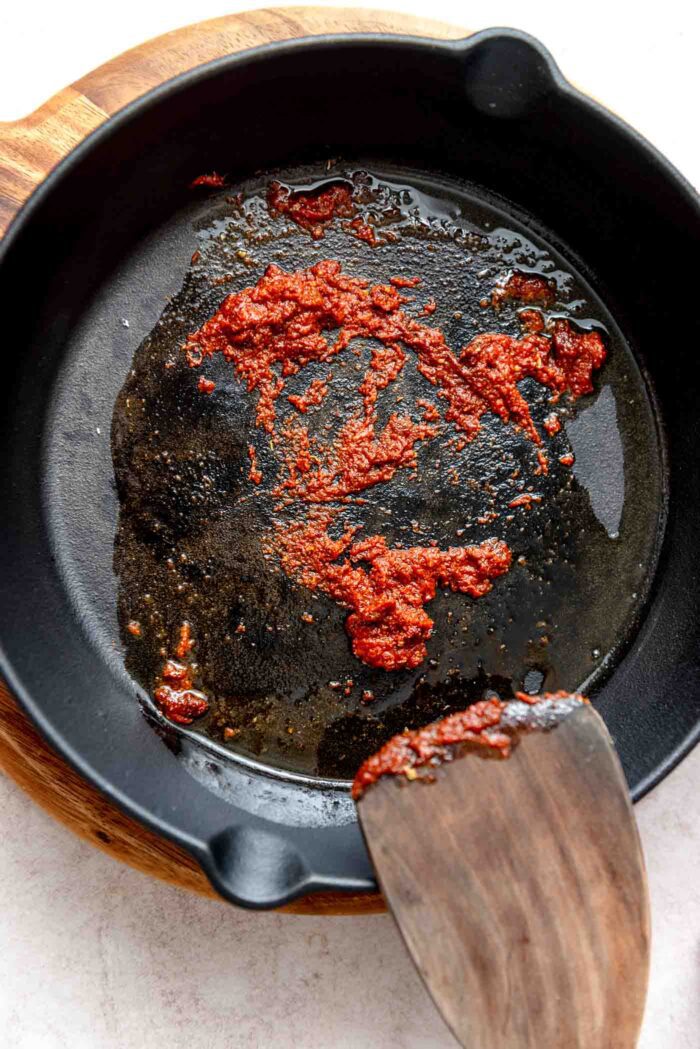 Taco seasoning and tomato paste cooking in a cast iron skillet.