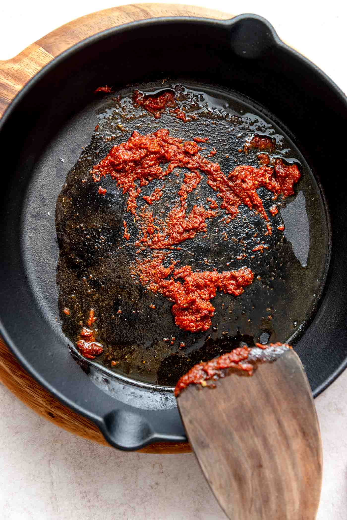 A cast iron skillet with taco seasoning and tomato paste cooking, releasing their aromatic flavors as they toast.