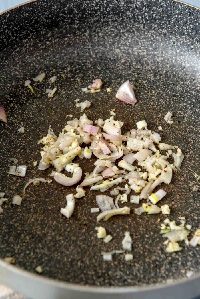 Minced garlic and shallot cooking in a large pan.