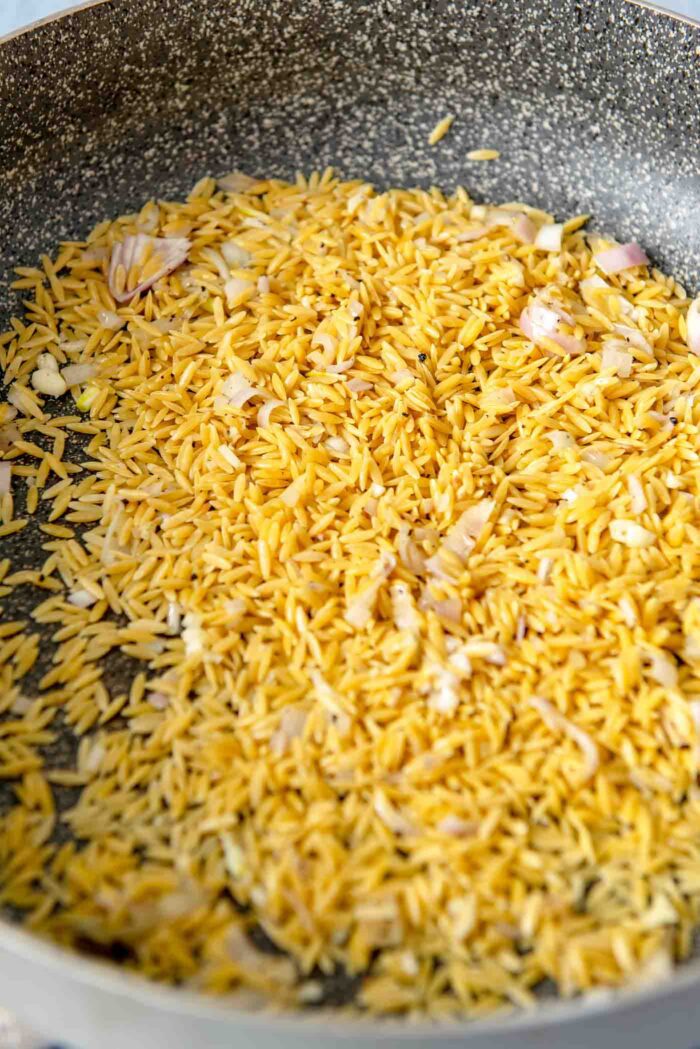 Dry orzo cooking in a pan.