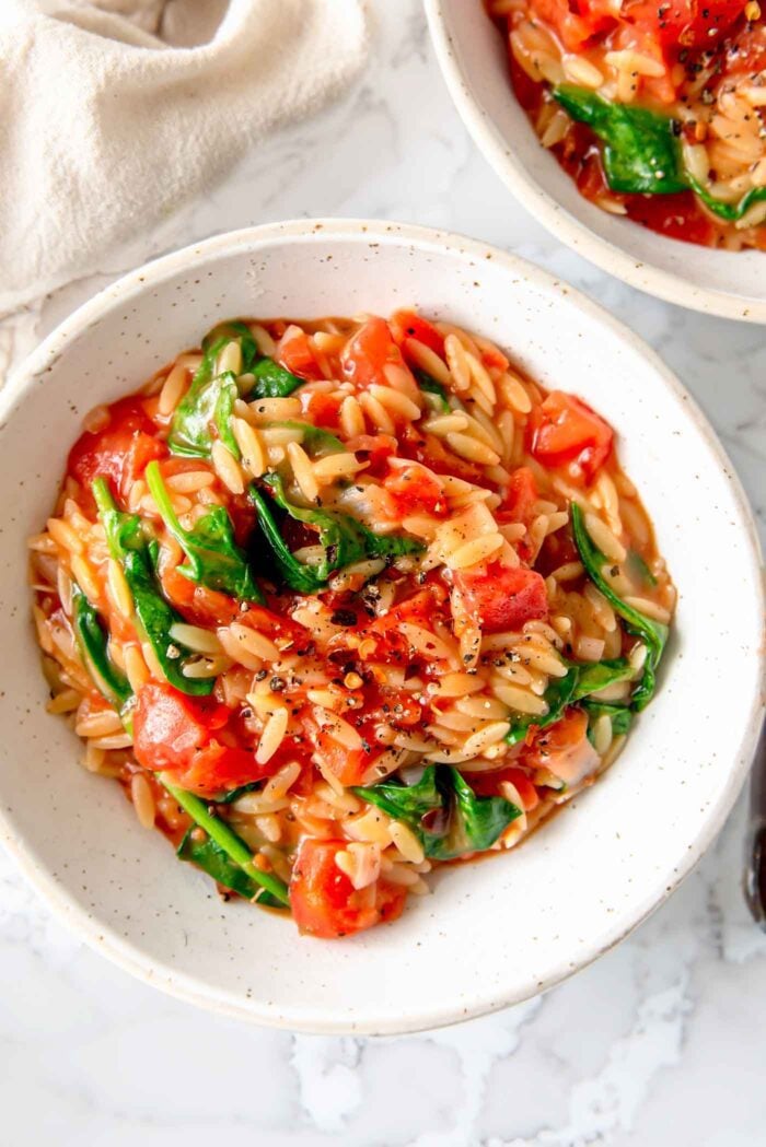 Bowl of tomato orzo with spinach.