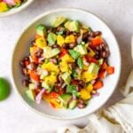 Bowl of mango and black bean salad with avocado, red bell pepper, red onion and cilantro.