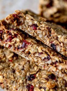 3 cranberry sunflower seed pumpkin seed granola bars leaning on each other on a piece of parchment paper.