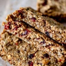 3 cranberry sunflower seed pumpkin seed granola bars leaning on each other on a piece of parchment paper.