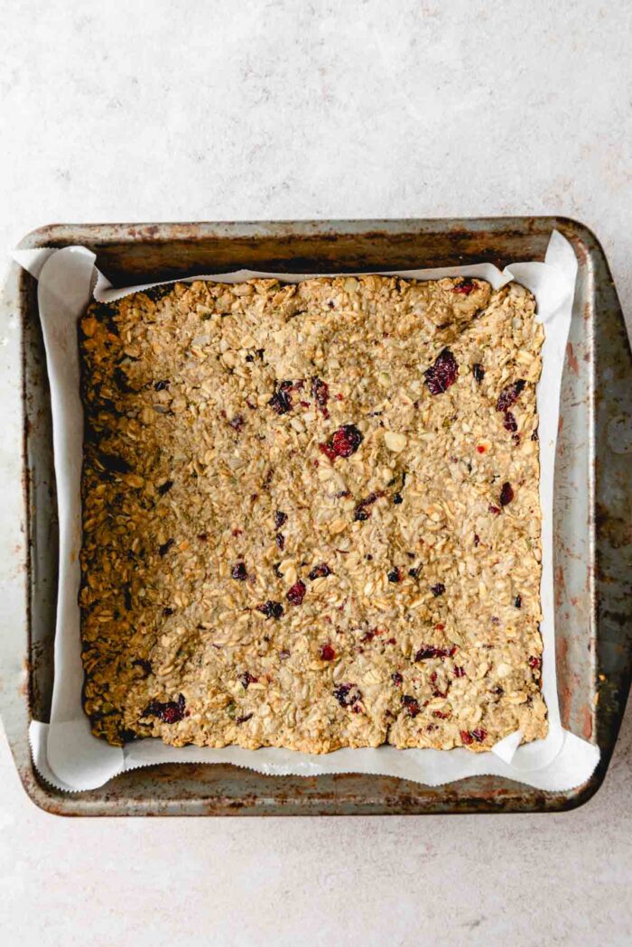 A square metal baking pan of baked cranberry granola bars.