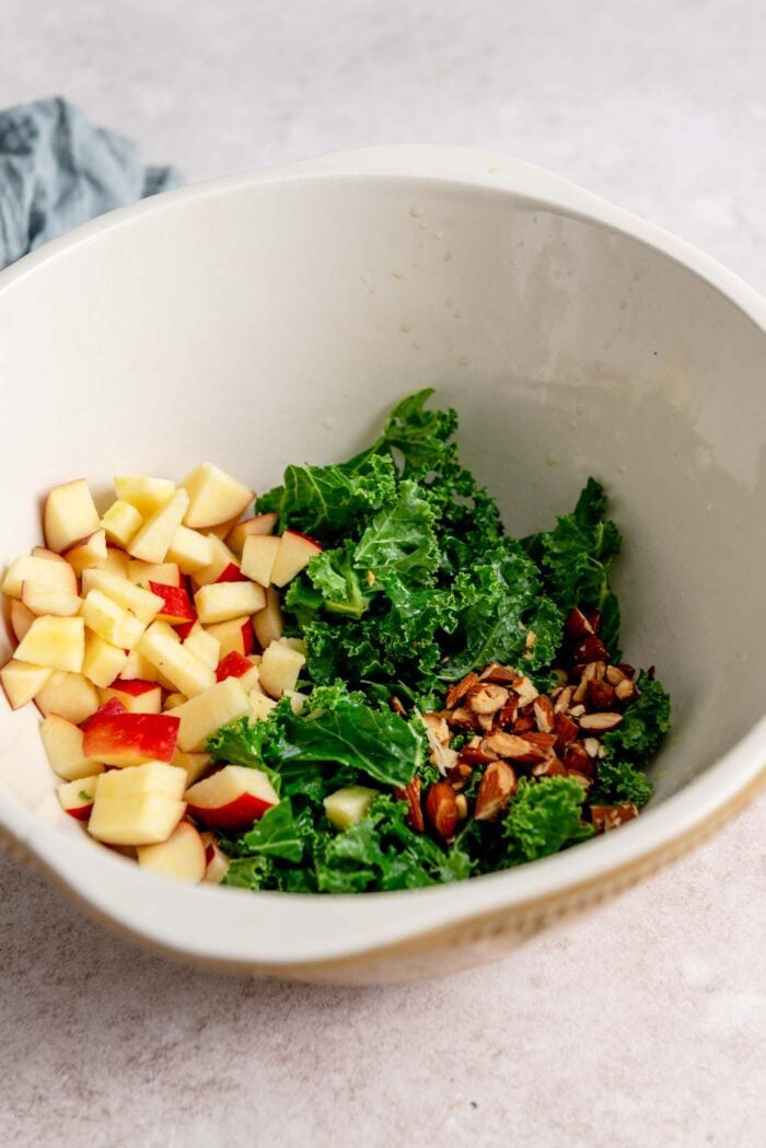 Chopped kale, diced apple and chopped almonds in a bowl.