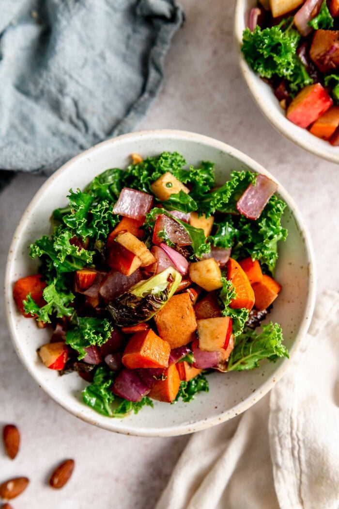 Roasted vegetable salad with kale, apple, sweet potato and red onion in a bowl.