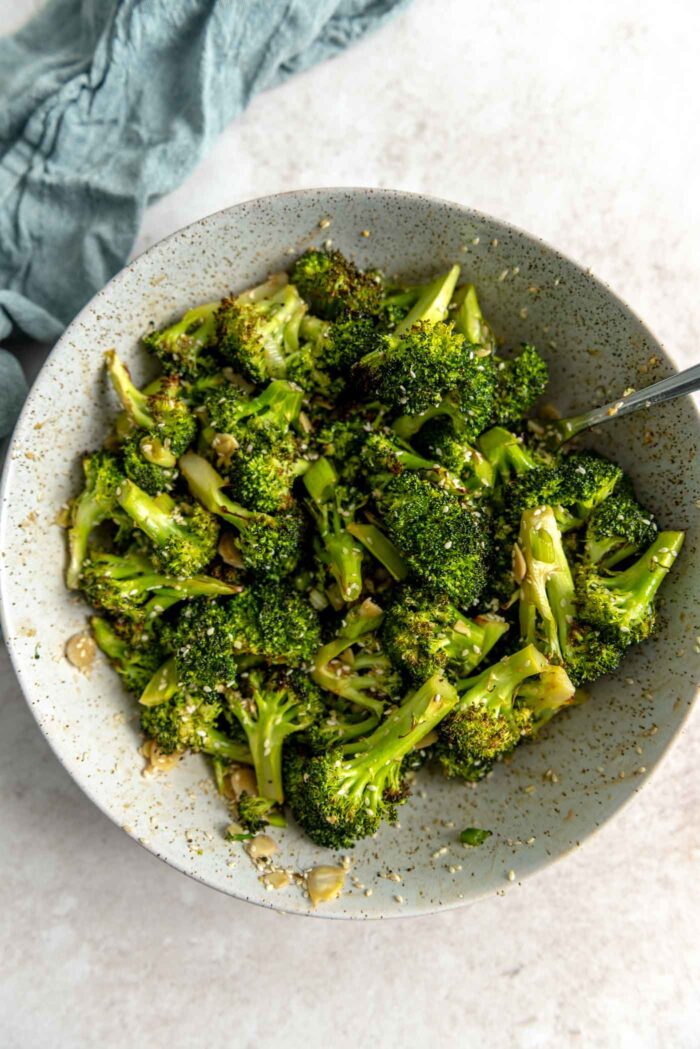 Roasted broccoli with almonds, sesame seeds and green onions in a bowl.