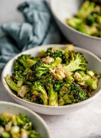 Bowl of roasted broccoli salad with slivered almonds and green onions.