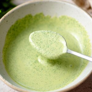 Spoon in a bowl of creamy cilantro tahini sauce.