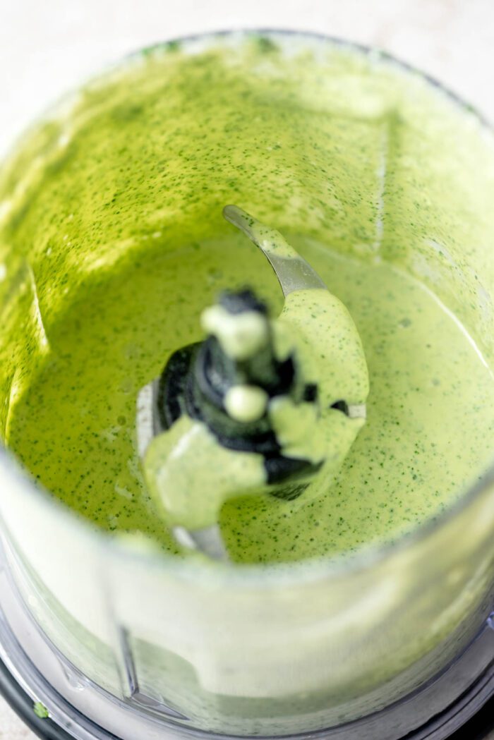 Green tahini sauce in a small blender.