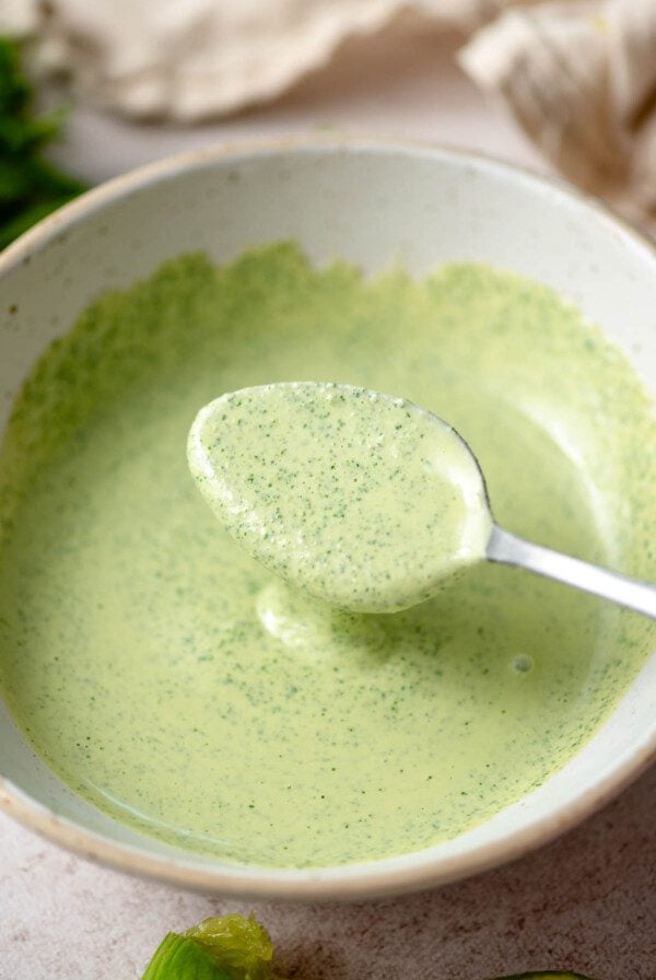 Spoon in a bowl of creamy cilantro tahini sauce.