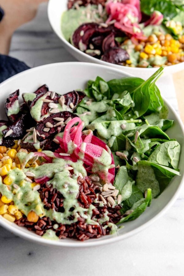 Wild rice bowl with chickpeas, spinach, pickled onion, corn and chickpeas on a marble cutting board. A second bowl is shown in the background.