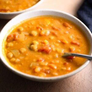 Bowl of creamy lentil chickpea soup with a spoon in it.