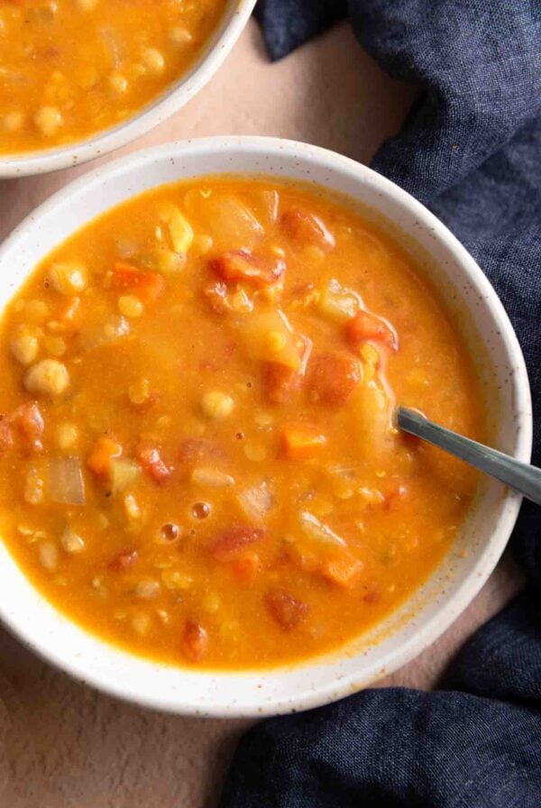 Bowl of creamy lentil chickpea soup with a spoon in it.