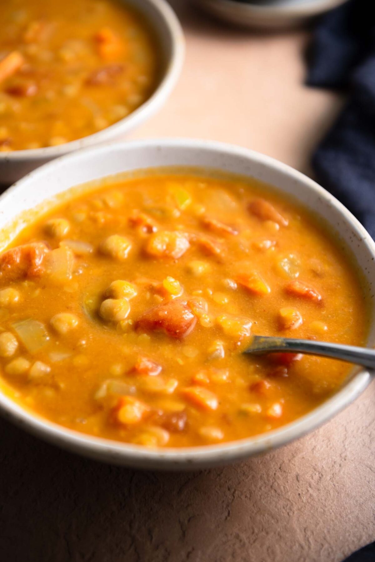 Bowl of creamy lentil chickpea soup with a spoon in it.