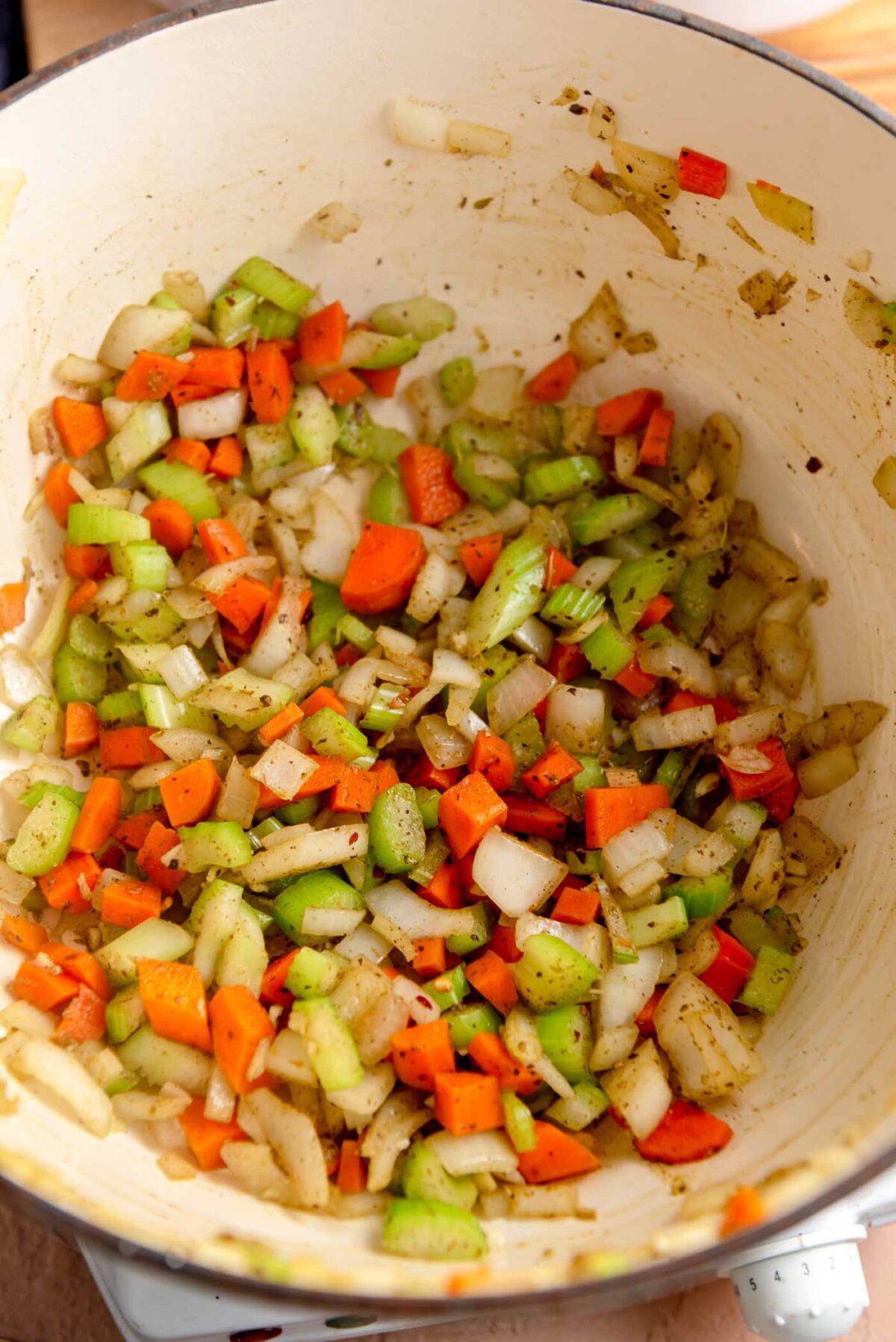 Carrot, celery, garlic, herbs and onion cooking in a soup pot.