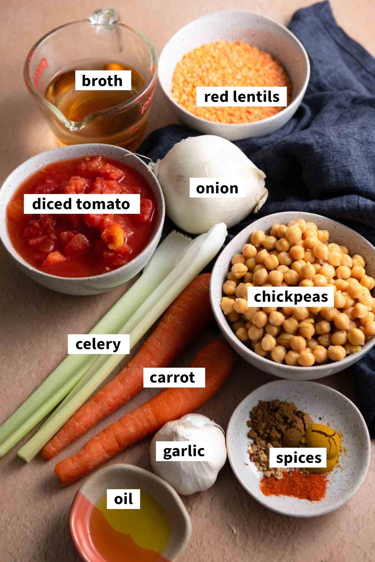 All ingredients for making a vegetarian red lentil chickpea soup with carrot, celery, garlic, onion and tomato.