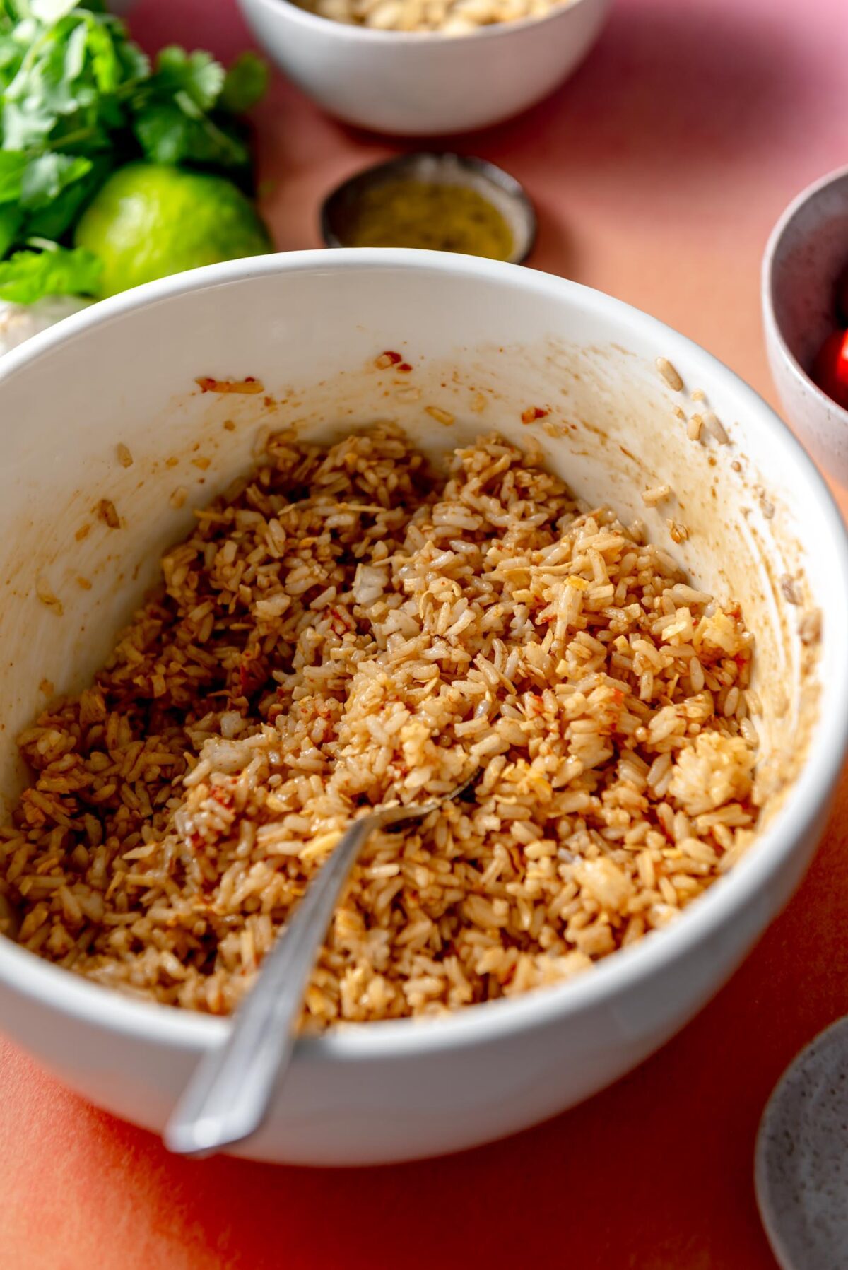 Cooked rice in a bowl mixed with coconut and red curry paste.