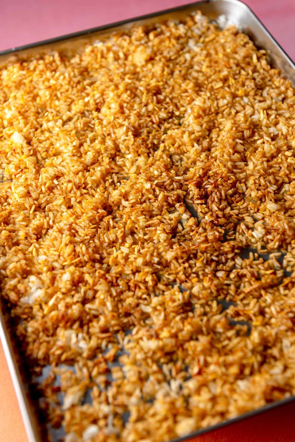 Baked rice spread out on a baking sheet.