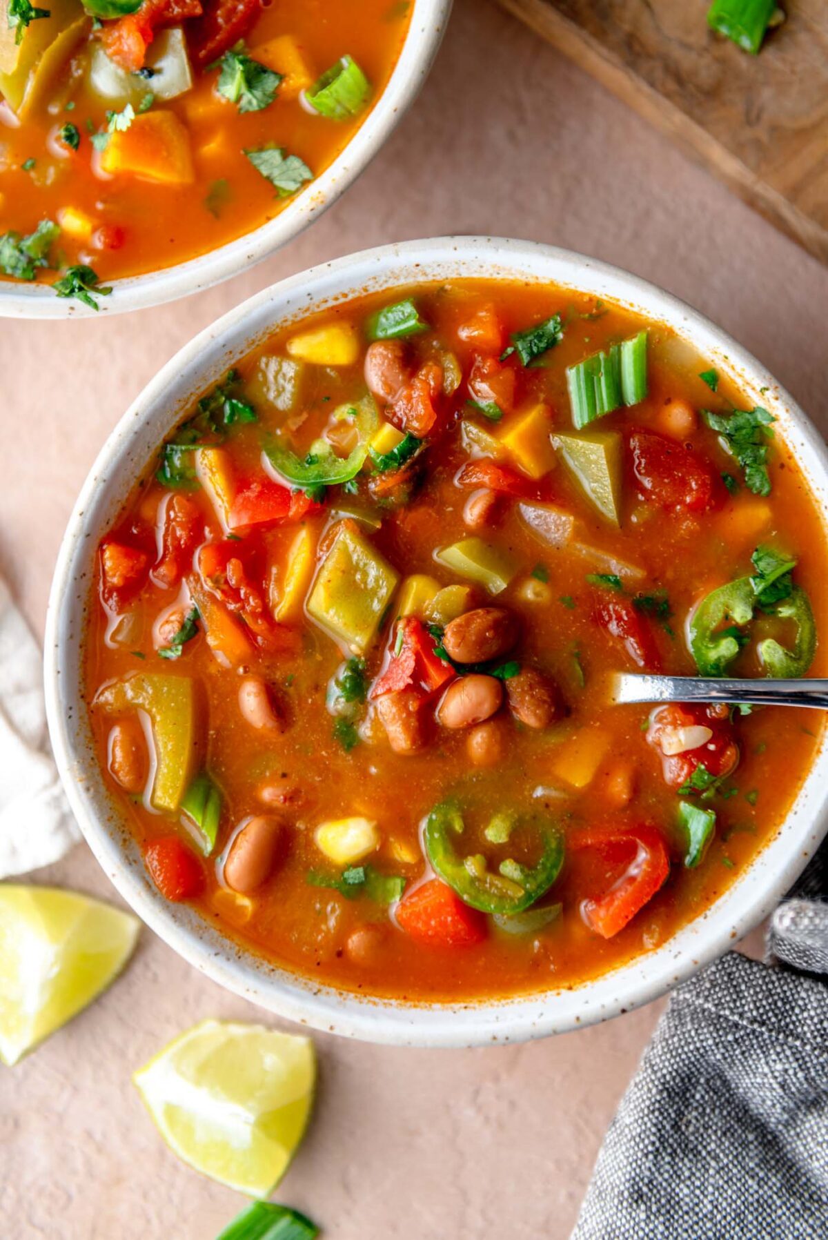 Bowl of enchilada soup with bell pepper, sweet potato, onion and cilantro in a tomato-based broth.