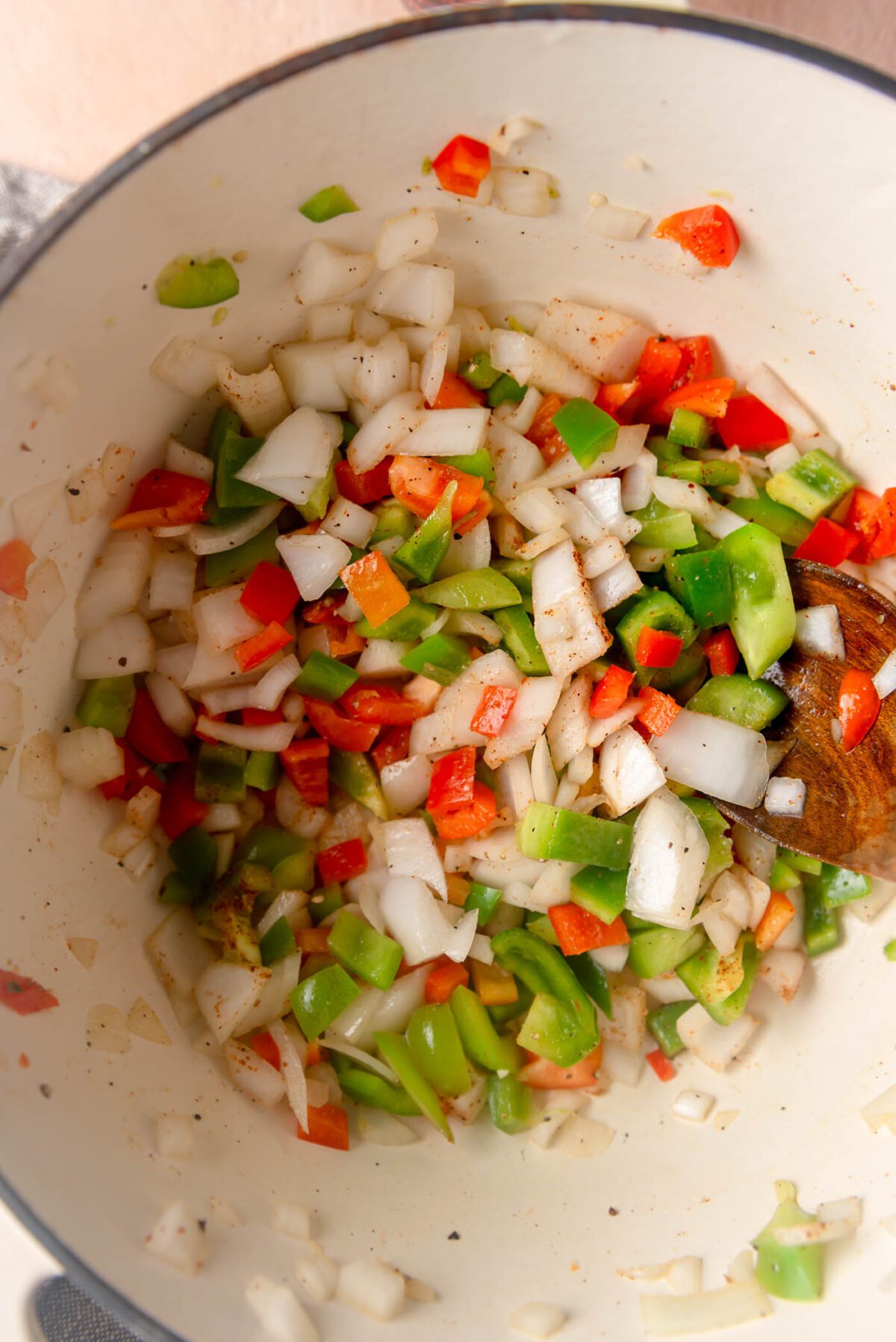 Diced onion and bell peppers cooking in spices in a large pot.