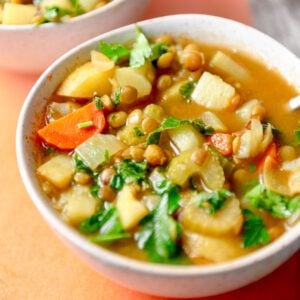 Bowl of a hearty soup with potatoes, carrots, lentils and kale.