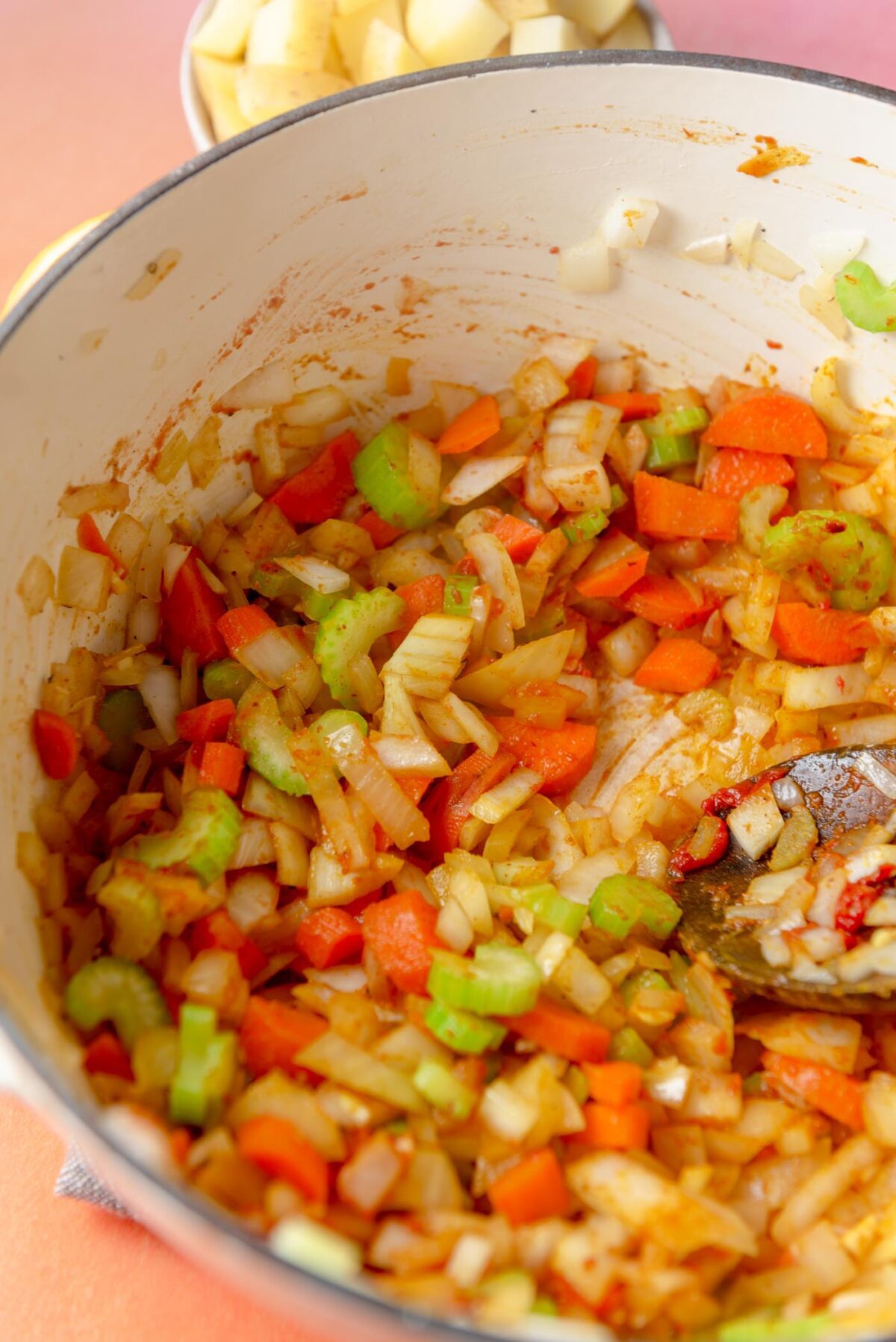 Chopped celery, onion, garlic, carrot and spices cooking in a soup pot.