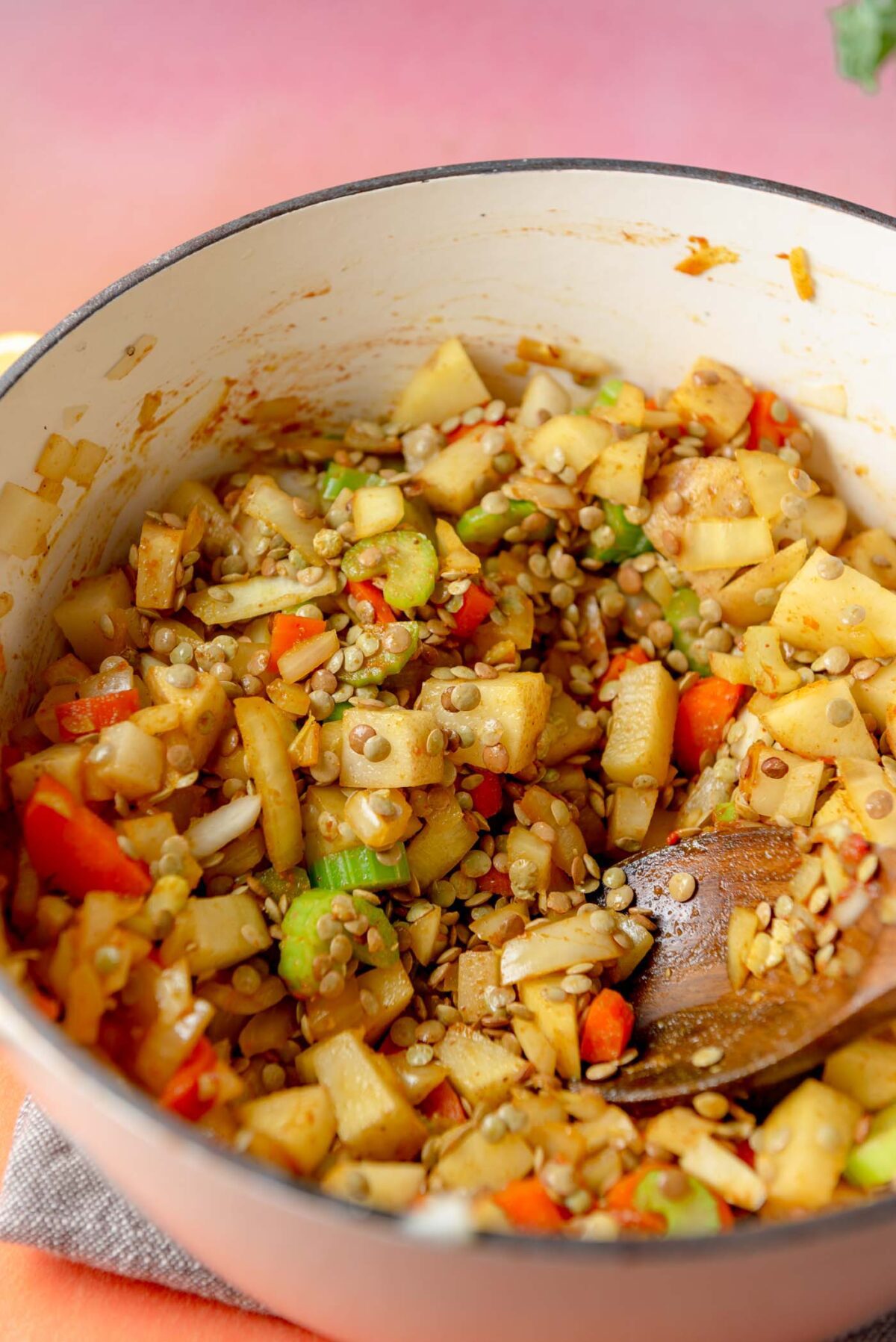 Carrot, potato, lentils, onions and celery cooking in a soup pot.