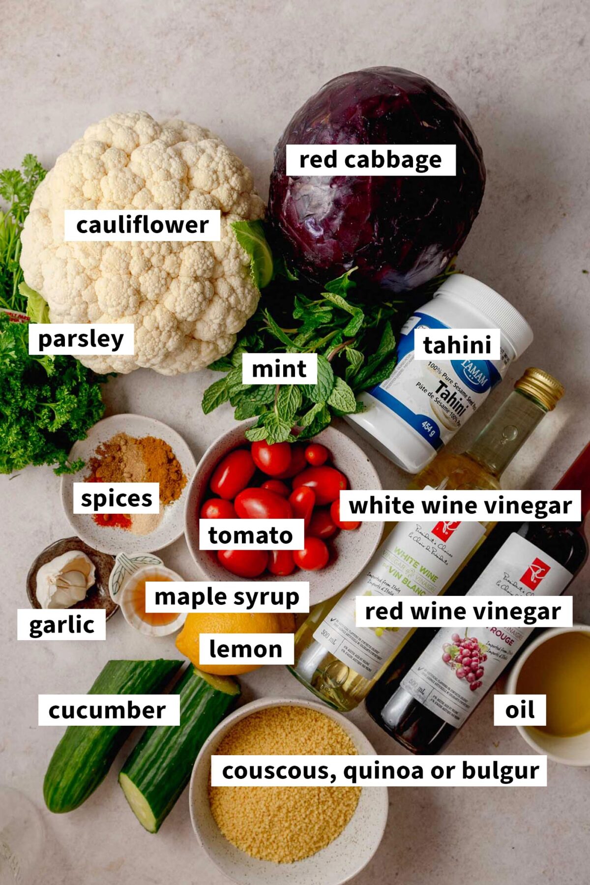 All the ingredients in bowls for making a cauliflower shawarma bowl with couscous, cabbage, spices, tahini sauce and pickled cabbage.