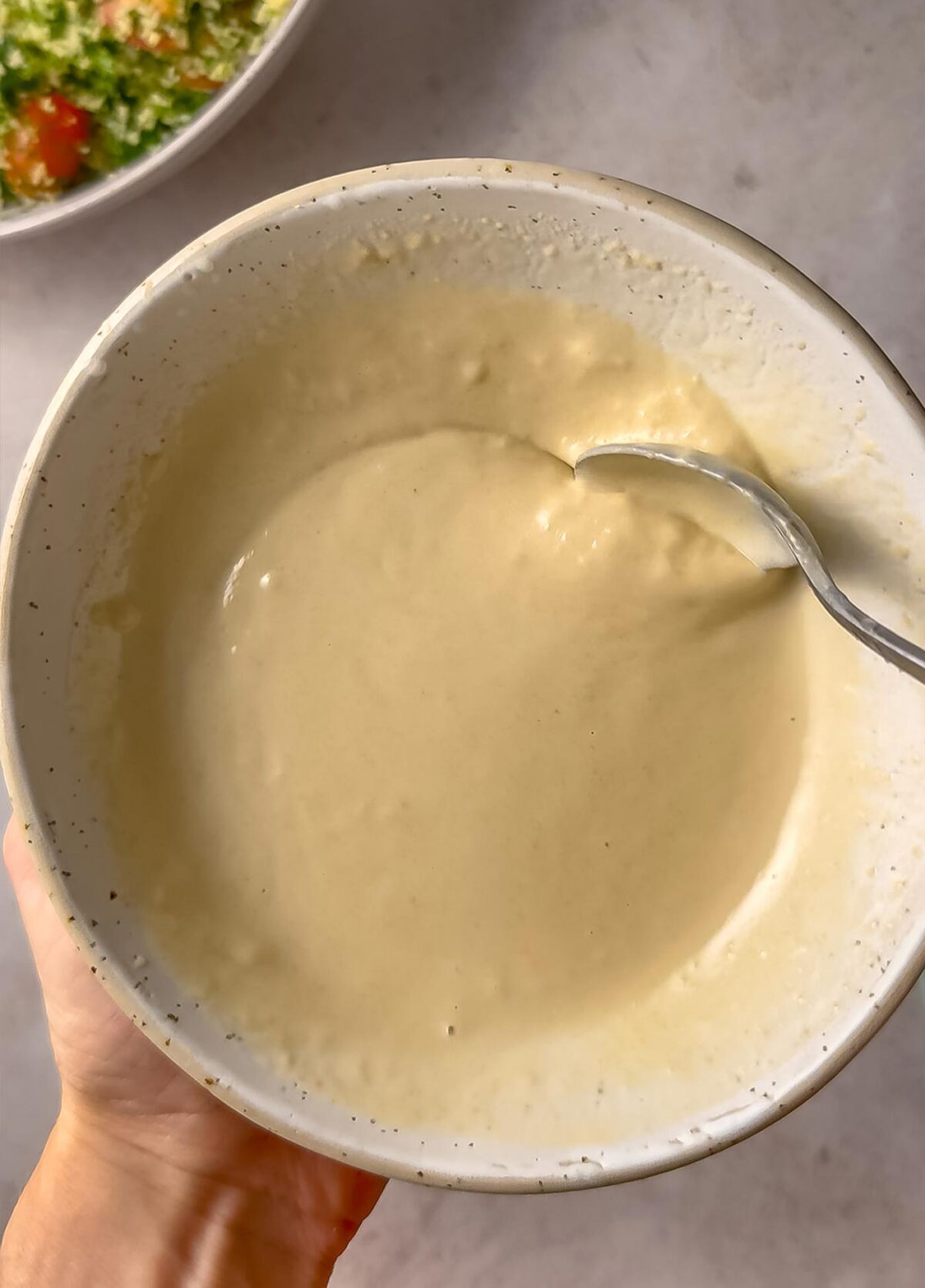 Creamy tahini dressing in a bowl with a spoon.