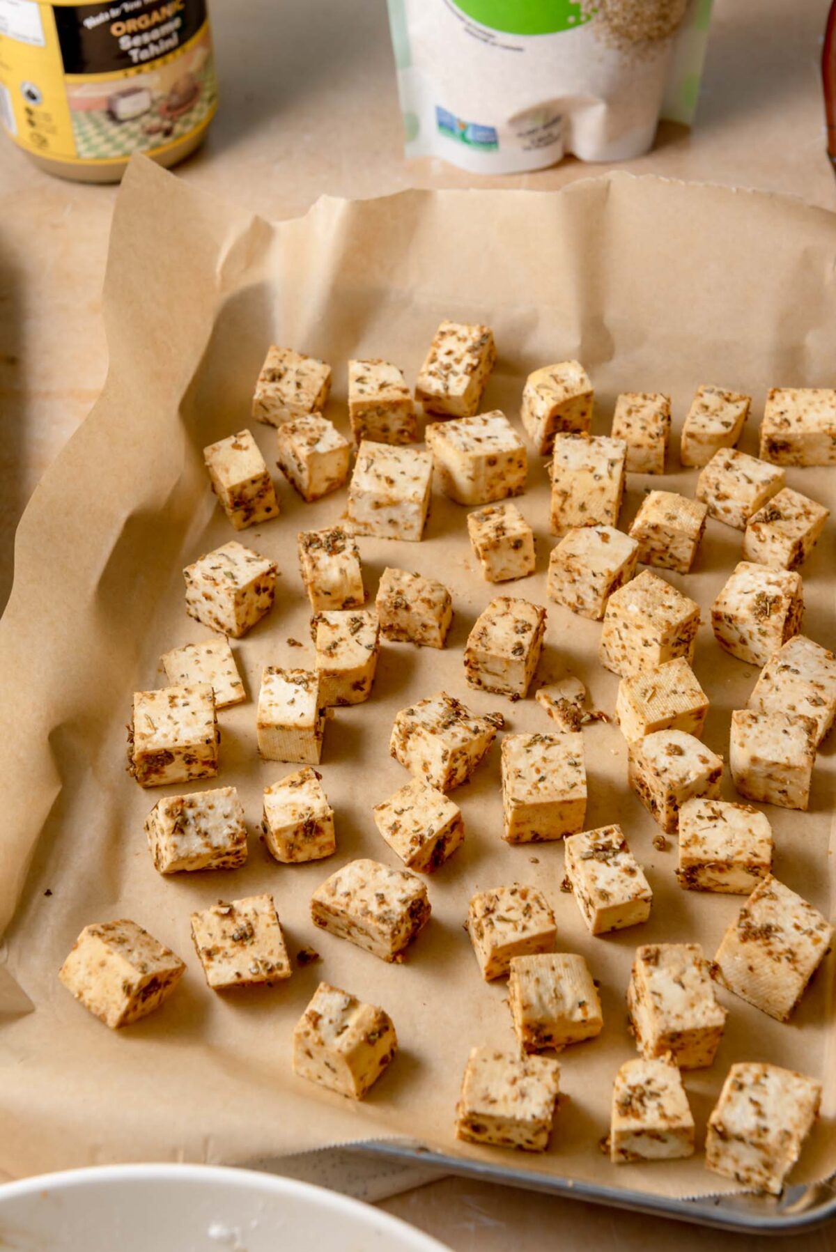 Seasoned tofu cubes arranged on a parchment-lined baking sheet ready for roasting.