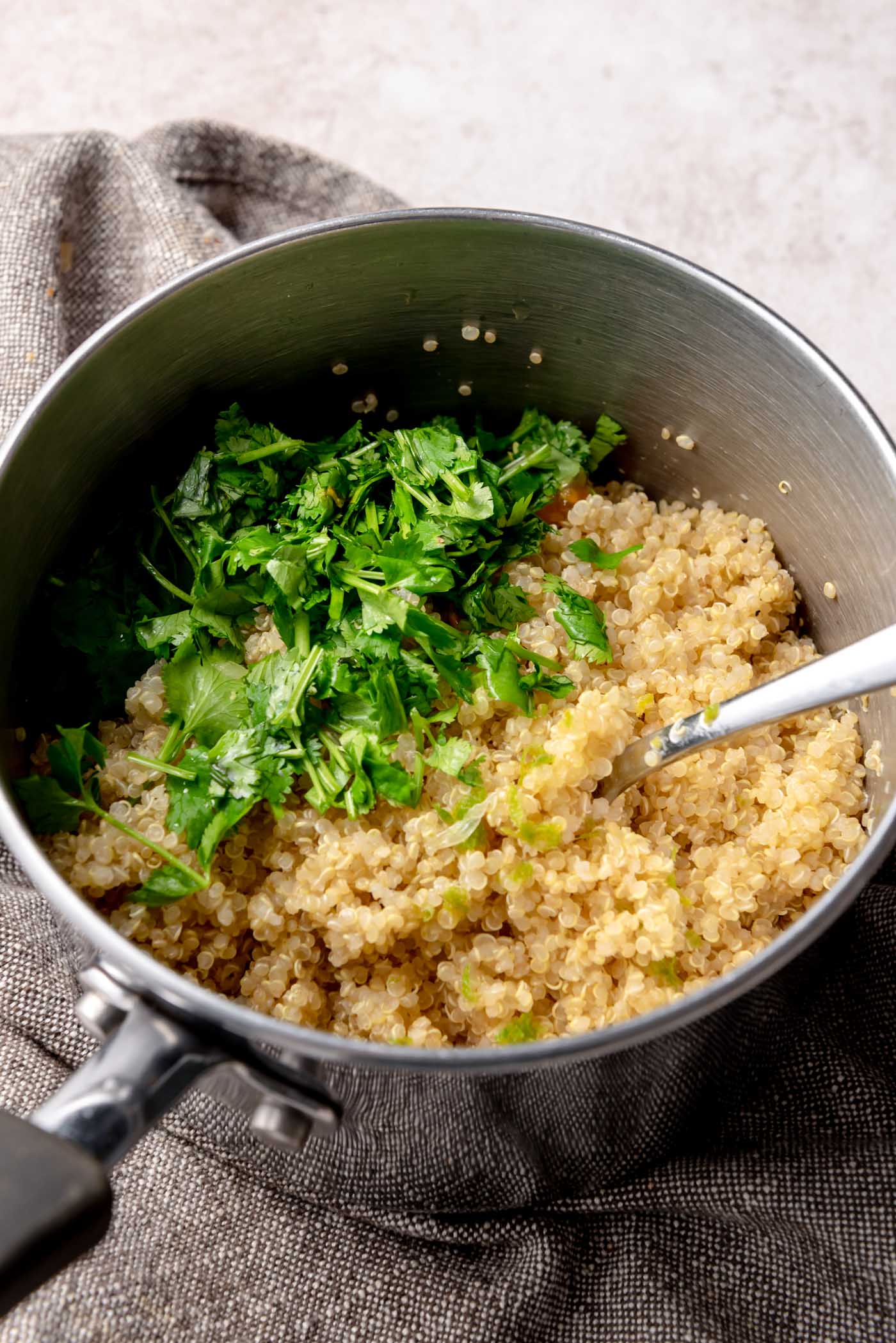 Cooked quinoa in a pot topped with freshly chopped cilantro, ready to be mixed.