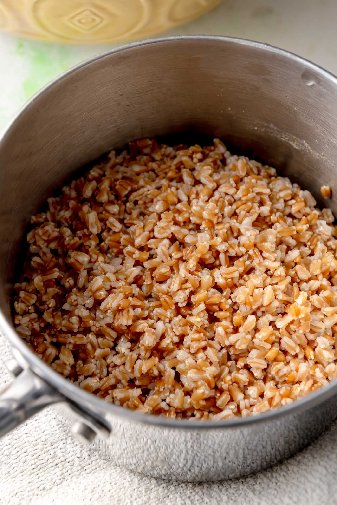 A saucepan filled with cooked farro, showing its chewy, golden-brown grains.