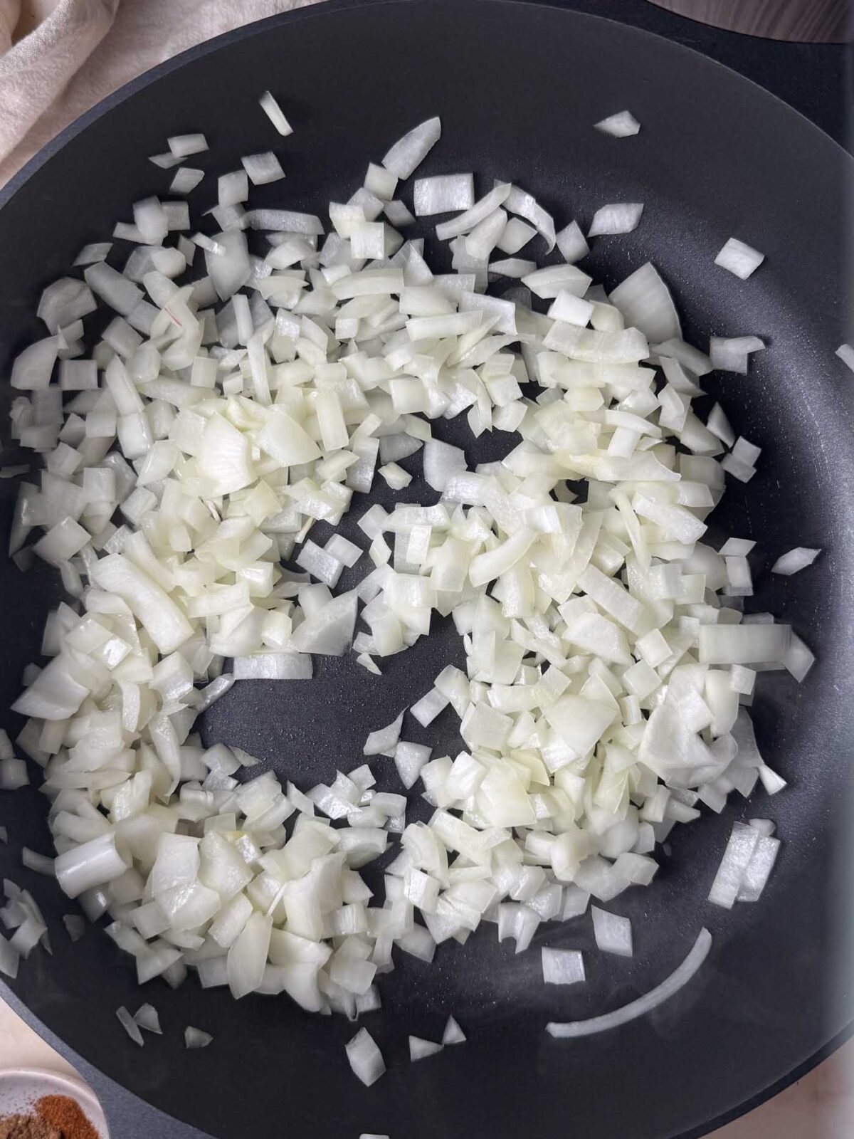 Chopped white onion saut&eacute;ing in a large nonstick pan before.